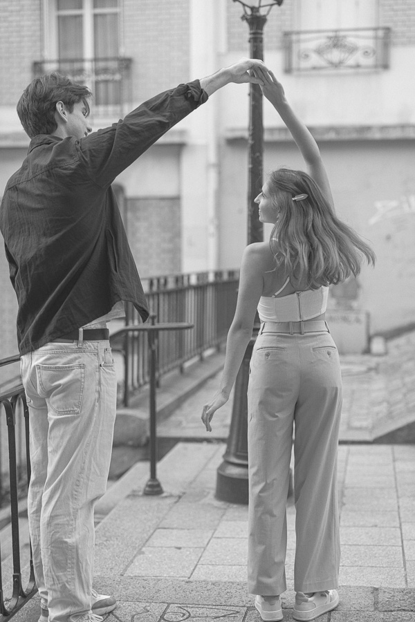 Black and white photo of couple dancing in Montmartre street during couple photo session Paris