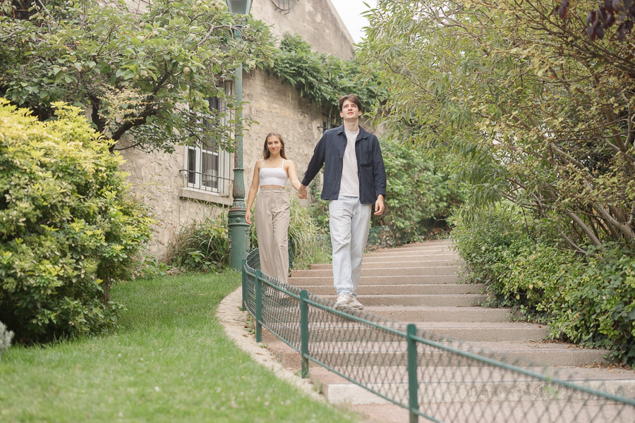 Couple walking hand in hand through golden light cobblestone street in Montmartre Paris