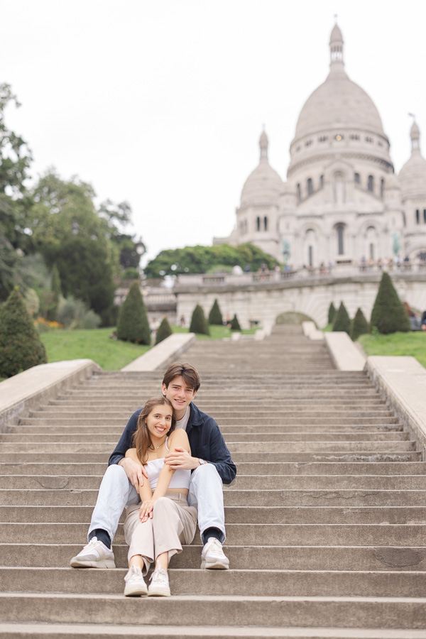 Couple sitting together on Sacré Coeur steps during couple photo session Montmartre Paris
