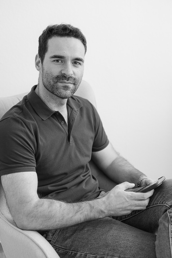 Natural black and white portrait of a man holding his phone, dating profile photo session in Geneva
