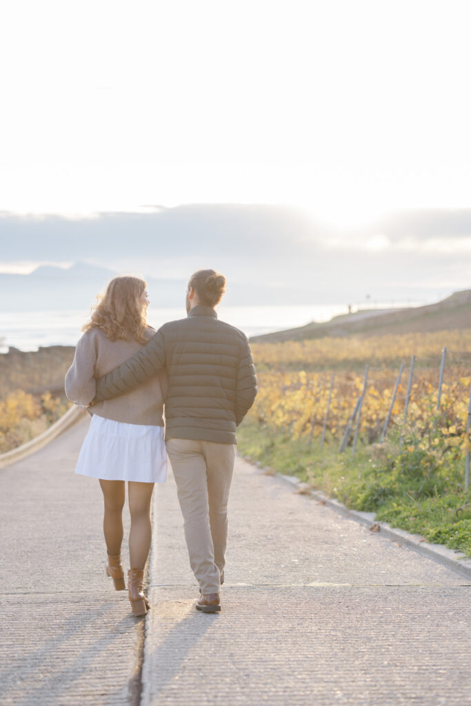 Couple walking hand in hand along vineyard path in Lavaux during engagement session