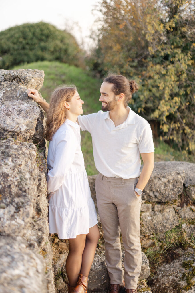 Couple laughing against stone wall during engagement session in Lavaux vineyards Switzerland