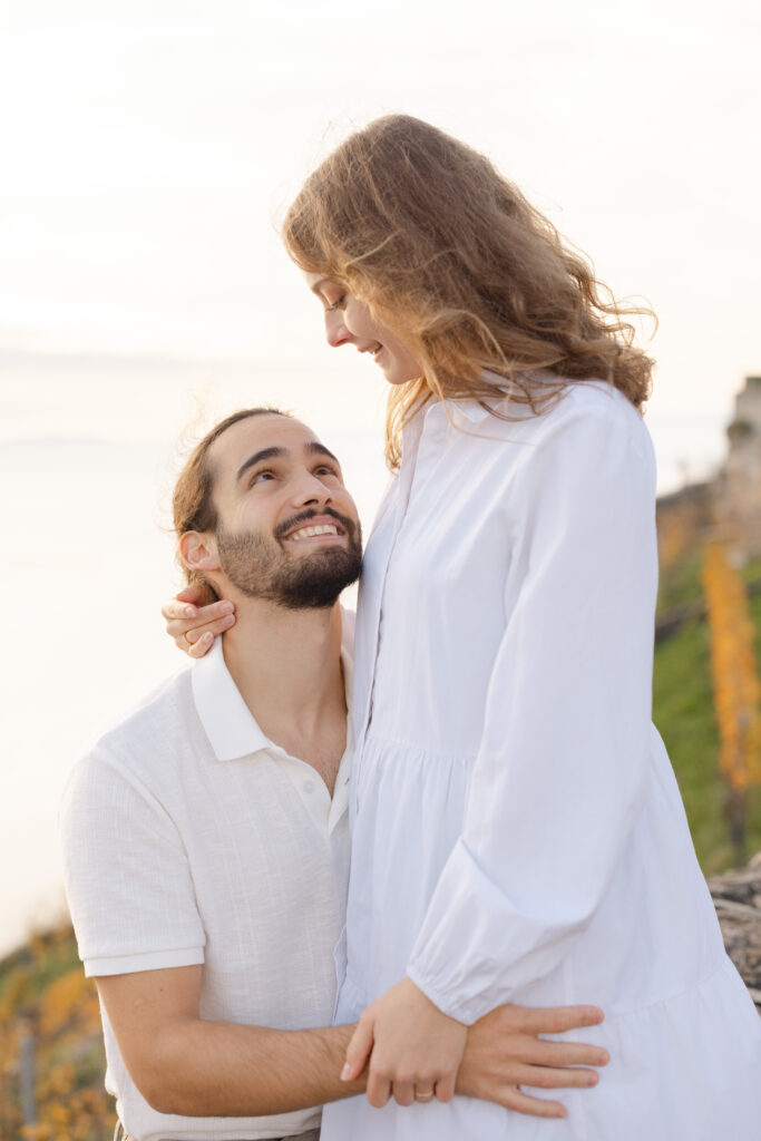 Groom looking up at bride laughing during engagement session in Lavaux vineyards