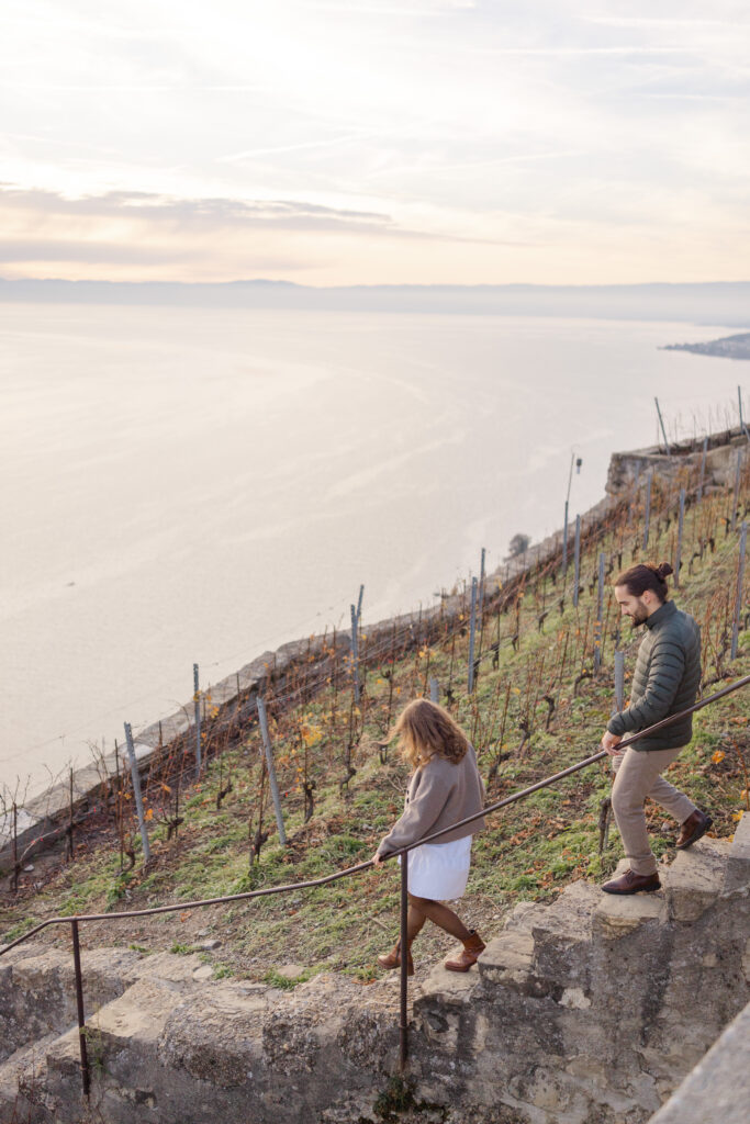 Aerial view of couple walking through Lavaux vineyard terraces with Lake Geneva below