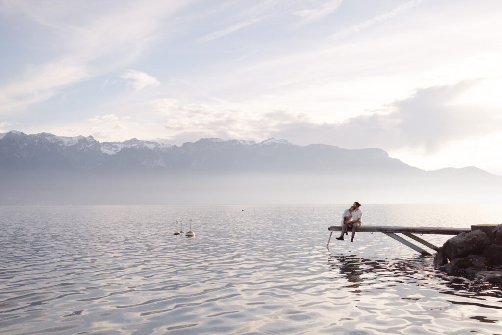 An intimate moment on the jetty over Lake Geneva during Tiphaine and Simaõ's engagement session. Photography by Mathilde Ballet.