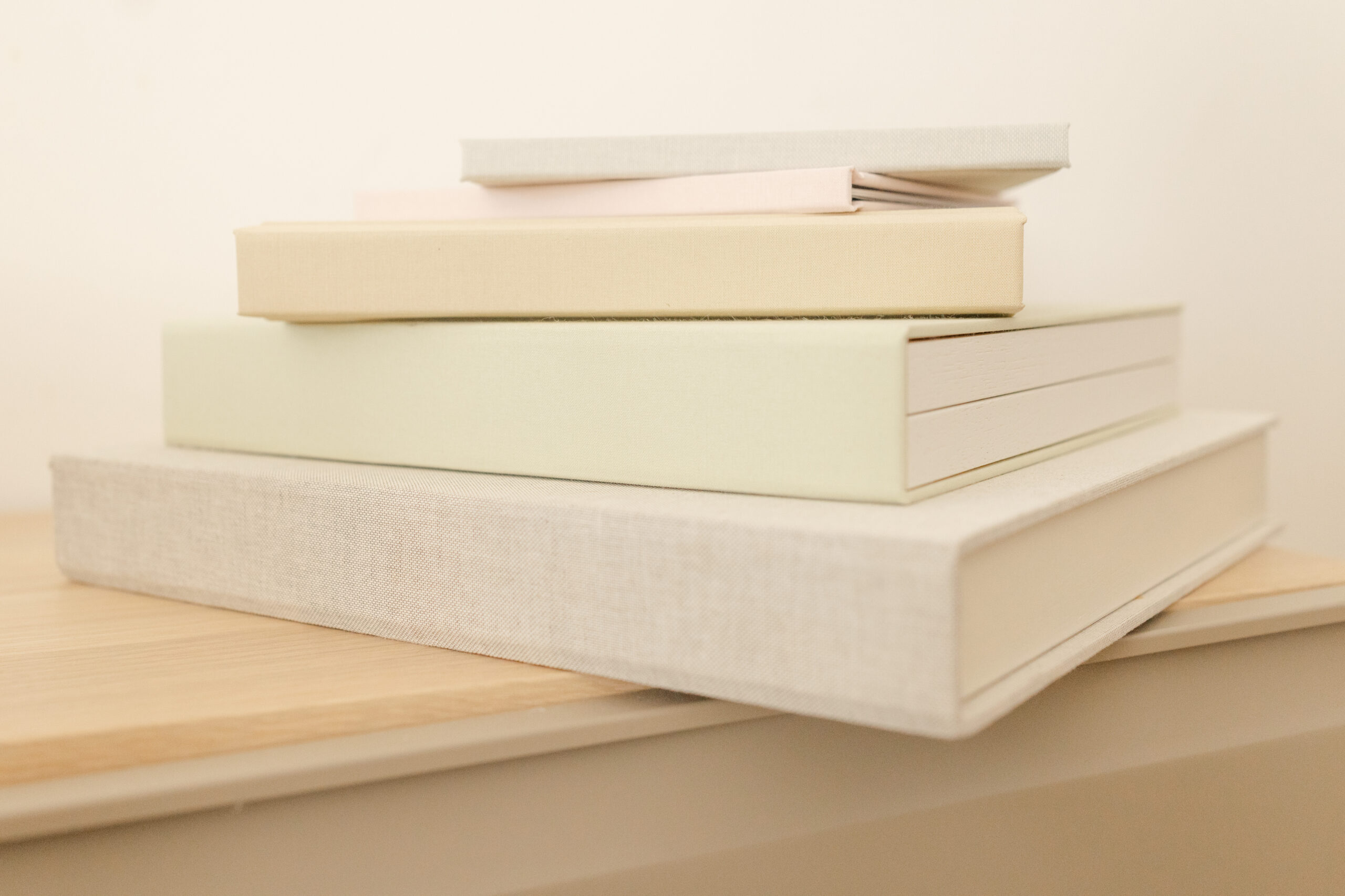 Stack of Floricolor linen cover photo albums in neutral tones on wooden surface Geneva