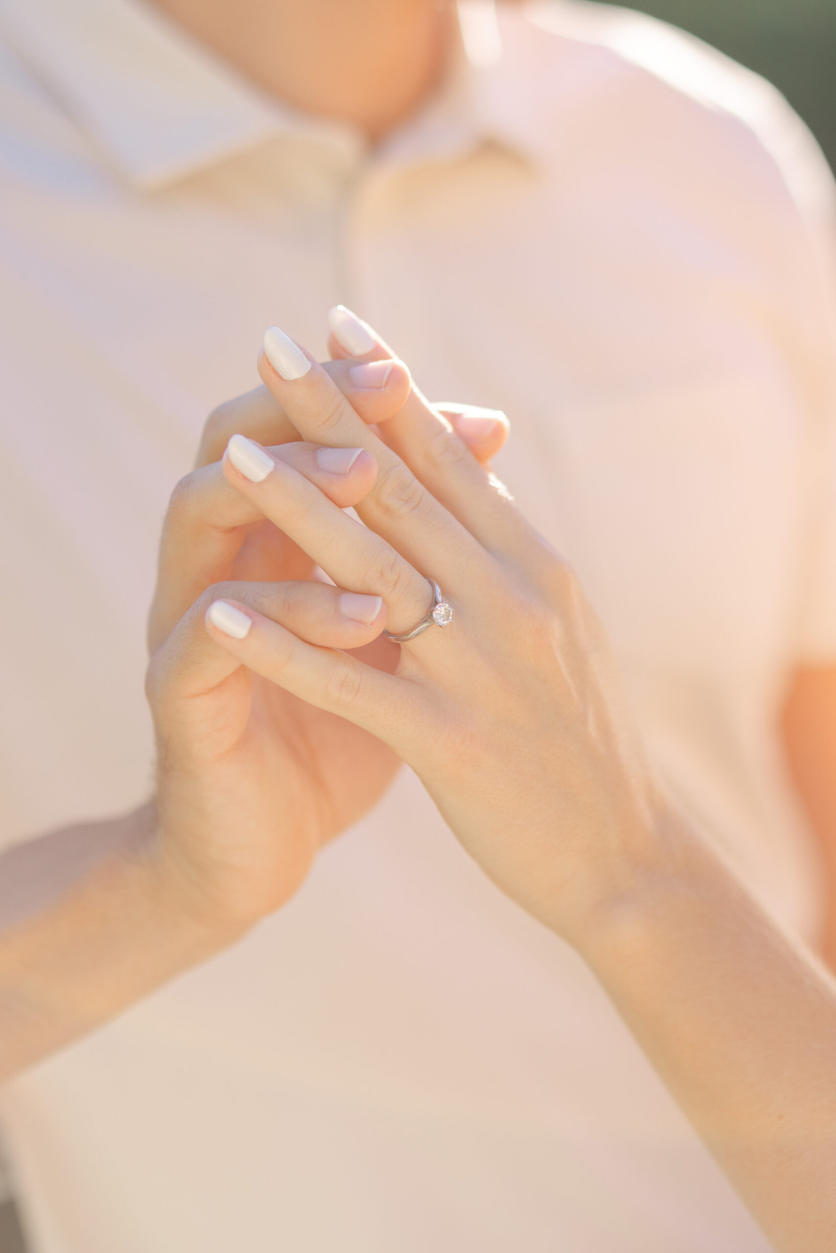 Close-up of a couple's hands after a surprise proposal, engagement ring on her finger, golden light